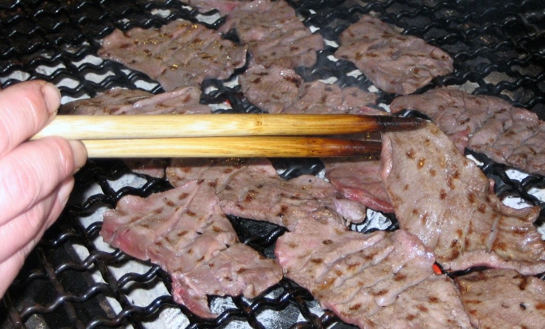 炭火の上で牛たんを焼く様子